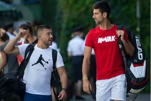 El argentino Badio y Djokovic, hace unos días, caminando por las instalaciones de Wimbledon; el santafecino trabaja con el serbio desde mayo de 2017
