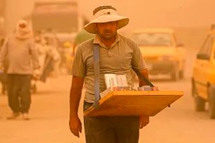 Un vendedor ambulante vende cigarrillos el lunes 16 de mayo de 2022 durante una tormenta de arena en Bagdad, Irak. (AP Foto/Hadi Mizban)