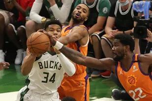Giannis Antetokounmpo pugna con Deandre Ayton (22) y Mikal Bridges; el griego hizo de todo para el triunfo de Milwaukee Bucks sobre Phoenix Suns por 109-103 que equilibró la final de la NBA.