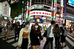 Las personas con mascarillas cruzan una calle en el área de Shinjuku de Tokio el 25 de mayo de 2020, día en que Japón levantó un estado de emergencia a nivel nacional por el coronavirus