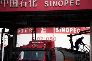 Un hombre que trabaja en una estación de servicio de Sinopec, en Shanghái; cinco importantes empresas chinas, incluidas dos de las mayores productoras de petróleo del país, dejarán de cotizar en la Bolsa de Valores de Nueva York, dijeron las firmas en documentos presentados el 12 de agosto de 2022. (Photo by Johannes EISELE / AFP)