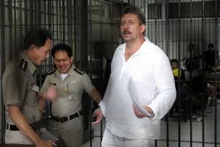 En esta foto de archivo tomada el 9 de abril de 2008, policías tailandeses se llevan al traficante de armas ruso Viktor Bout después de tomarle las huellas dactilares en el centro de detención del tribunal penal de Bangkok. Moscú confirmó el 8 de diciembre de 2022 que había intercambiado a la estrella del baloncesto estadounidense Brittney Griner, que había estado encarcelada en Rusia, por el notorio traficante de armas Victor Bout, que cumplía una condena de 25 años en los Estados Unidos. (Photo by Saeed KHAN / AFP)