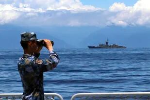 En esta imagen, distribuida por la agencia noticiosa china Xinhua, un soldado del Ejército Popular de Liberación mira a través de unos prismáticos durante unas maniobras militares, con la fragata taiwanesa Lan Yang de fondo, el 5 de agosto de 2022. (Lin Jian/Xinhua vía AP)