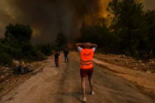 Unas personas corren lejos del poblado de Sirtkoy, en Antalya, Turquía, el domingo 1 de agosto de 2021, luego de que fue devastado por un incendio forestal. (AP Foto)