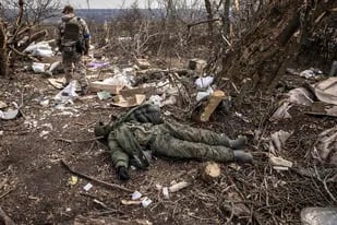 Un soldado ucraniano pasa junto al cuerpo de un soldado ruso que yacía en el suelo después de que las tropas ucranianas recuperaran la aldea de Mala Rogan, al este de Kharkiv, el 30 de marzo de 2022. (Photo by FADEL SENNA / AFP) / UKRAINE - RUSSIA CONFLICT 100 DAYS 100 PICTURES