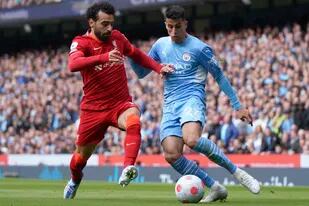 Mohamed Salah (izquierda) de Liverpool, disputa el balón con Joao Cancelo de Manchester City durante el partido de la Liga Premier, en Manchester, el domingo 10 de abril de 2022. (AP Foto/Jon Super)