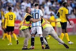 Uno de los hinchas que invadió el campo de juego (tapado por Messi) es tackleado por personal de seguridad