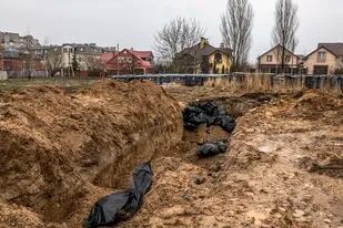 Los cuerpos de los civiles que, según las autoridades, fueron asesinados por las fuerzas rusas yacen en una fosa común frente a la iglesia de San Andrés en Bucha, Ucrania, el domingo 3 de abril de 2022.
