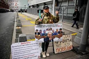Una mujer sostiene un cartel en apoyo del presidente ruso Vladimir Putin en el centro de Moscú el 22 de septiembre de 2022, que reformula un eslogan soviético de la Segunda Guerra Mundial: "¡Todo por el Frente! Todo por la victoria!".