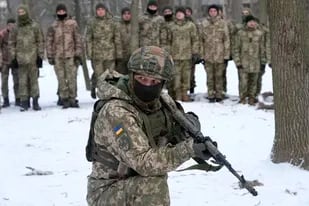 Un instructor capacita a miembros de las fuerzas de defensa de Ucrania, en un parque de Kiev, el sábado 22 de enero de 2022
