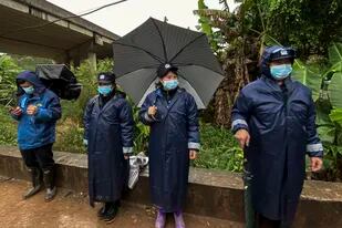 Varios agentes hacen guardia bajo la lluvia en una carretera que lleva a la aldea de Molang, cerca del lugar donde se estrelló el vuelo 5735 de China Eastern, el 24 de marzo de 2022, en la provincia de Guangxi, en el suroeste de China. (AP Foto/Ng Han Guan)