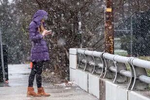 Bridget Step revisa su teléfono celular mientras cae nieve, el domingo 16 de enero de 2022, en Atlanta. (Foto AP/Ben Gray)