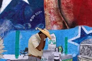 Con un mural con la bandera de Texas de fondo, un hombre de ajusta el tapabocas en el barrio hispano de Oak Cliff, en Dallas, el 22 de septiembre del 2021. (AP Photo/LM Otero)