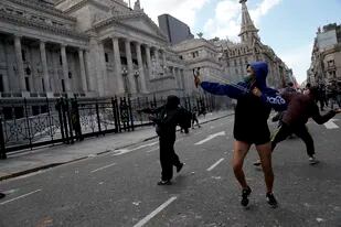 Un manifestante apunta su honda durante una protesta frente al Congreso mientras los legisladores se preparan para votar una ley para ratificar el acuerdo del gobierno con el Fondo Monetario Internacional, el jueves 10 de marzo de 2022. (AP Foto/Rodrigo Abd)