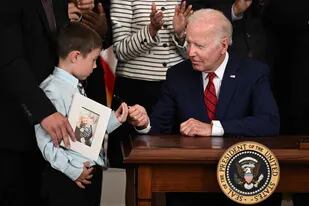 El presidente de EE. UU., Joe Biden, entrega un bolígrafo al hijo de la difunta oficial del Cuerpo de Marines, Kate Thomas, antes de viajar a Los Ángeles para la Cumbre de las Américas