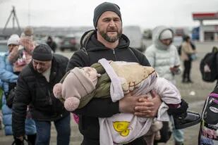 Un hombre con un niño en brazos en el paso fronterizo de Porubne, a 5 de marzo de 2022, en el oeste de Ucrania.