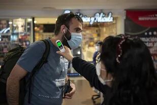 A un pasajero le toman la temperatura en el Aeropuerto Internacional Arturo Merino Benítez, en Santiago de Chile