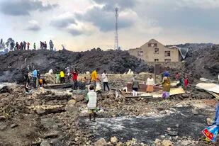 La gente se reúne en una corriente de roca de lava fría después de la erupción nocturna del monte Nyiragongo en Goma, Congo.