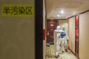 Empleados desinfectan un hotel usado para cuarentenas en Shangai