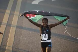 La keniata Irine Kimais despliega la bandera de su país luego de conseguir la victoria en la Media Maratón de Buenos Aires