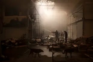 Varias personas intentan extinguir un incendio en un mercado tras un ataque ruso, en Járkiv, Ucrania, el 25 de marzo de 2022. (AP Foto/Felipe Dana)