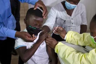 Archivo - Un niño gesticula mientras recibe una inyección de la vacuna de Pfizer contra el COVID-19 en Diepsloot Township cerca de Johannesburgo, el jueves 21 de octubre de 2021. (AP Foto/Denis Farrell, Archivo)