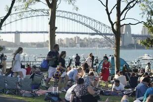 La gente se reúne frente al Sydney Harbour Bridge, antes de los fuegos artificiales de Nochevieja en Sydney, Australia, el viernes 31 de diciembre de 2021.