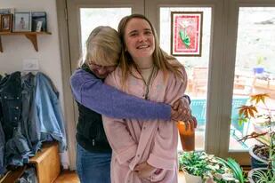 Karen McCulloch (izq) abraza a su hija Kirsten en su casa el 10 de marzo del 2022. La muchacha luce la bata de su abuela Mary Jacq McCulloch en su casa de Hillsborough, Carolina del Norte. La abuela falleció tras contraer el COVID-19 en abril del 2020. (AP Photo/David Goldman)