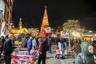 La gente se reúne por la noche alrededor del árbol de Navidad gigante afuera de la Iglesia Ortodoxa Griega de la Anunciación en la ciudad de Nazaret, en el norte de Israel, el 18 de diciembre de 2021