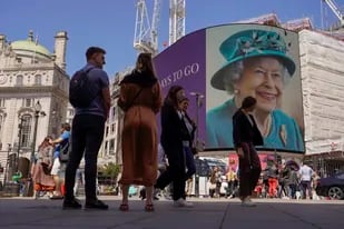 La gente pasa frente a la pantalla en Piccadilly Circus mientras muestra una cuenta regresiva de 7 días para el Jubileo de Platino de la reina, con dos fotos de Isabel de Gran Bretaña, en Londres, el viernes 27 de mayo de 2022.(AP Photo/Alberto Pezzali)