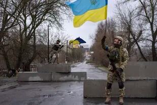 Un soldado ucraniano levanta una bandera de su país en Bucha, en las afueras de Kiev, el 3 de abril del 2022. Rusia sufrió un revés de proporciones históricas al no poder tomar la capital de Ucrania. (AP Photo/Rodrigo Abd, File)