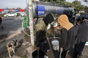Vecinos de la villa 1-11-14 reciben agua de una camión de Aysa