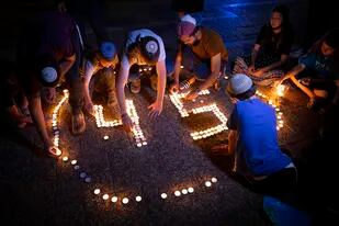 En esta imagen de archivo, jóvenes israelíes encienden velas en memoria de los 45 judíos ultraortodoxos muertos en una estampida en una festividad religiosa, durante una vigilia, en Tel Aviv, Israel, el 2 de mayo de 2021. (AP Foto/Oded Balilty, archivo)