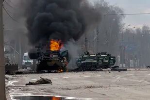 ARCHIVO - Un vehículo blindado ruso de transporte de tropas arde entre vehículos ligeros dañados y abandonados tras combates en Járkiv, la segunda ciudad más grande de Ucrania, el 27 de febrero de 2022. (AP Foto/Marienko Andrew, Archivo)