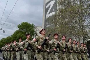 Elementos de la Guardia Nacional de Rusia marchan por una calle mientras en un edificio al fondo se ve la imagen de la letra Z, que se ha convertido en un símbolo del ejército de Rusia, el jueves 5 de mayo de 2022, en Sebastopol, Crimea. (AP Foto)