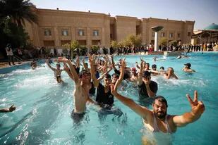 Partidarios del clérigo chiita iraquí Moqtada Sadr nadan en la piscina de la sede del gobierno en la Zona Verde de la capital Bagdad, el 29 de agosto de 2022