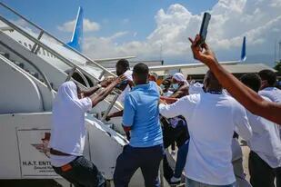 Haitianos deportados de Estados Unidos tratan de subir al mismo avión en el que viajaron a su país de origen, en el Aeropuerto Toussaint Louverture, en Puerto Príncipe, Haití