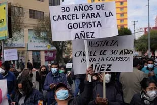 Las personas sostienen carteles afuera de la prisión de mujeres de Miraflores donde se encuentra la expresidenta interina de Bolivia, Jeanine Áñez, al inicio de un juicio en su contra en La Paz, Bolivia, el lunes 28 de marzo de 2022. (AP Foto/Juan Karita)