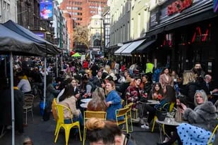 Personas beben y comen en cafés y tabernas al aire libre en Soho, en el centro de Londres