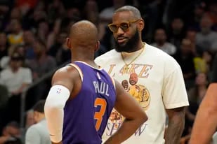 LeBron James, que anoche no pudo actuar en los Lakers por una lesión, habla con el jugador de Phoenix Chris Paul (3); Los Ángeles cayó y ya no podrá entrar en los playoffs de la NBA.