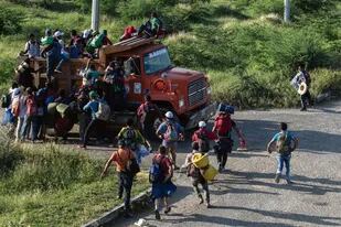 Migrantes de la caravana de hondureños rumbo a Estados Unidos trepan a un camión en Oaxaca, México