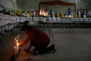 Una mujer enciende velas en honor a las personas que fueron asesinadas durante la guerra contra Sendero Luminoso luego de que las autoridades devolvieran a las familias los restos de las víctimas, durante una vigilia en Accomarca, Perú, el miércoles 18 de mayo de 2022.  (AP Foto/Martín Mejía)