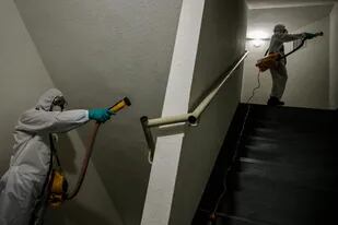 Empleados de sanidad desinfectan un edifico en Santiago