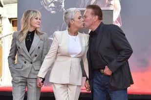 De la mano, tres íconos del cine: Melanie Griffith sonríe ante el beso de Jamie Lee Curtis y Arnold Schwarzenegger en la alfombra roja del TCL Chinese Theatre de Hollywood