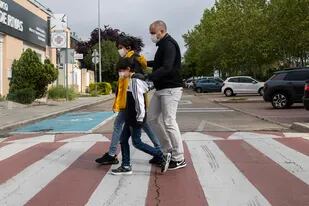 Una familia que usan mascarillas en un cruce peatonal en Rivas Vaciamadrid, España