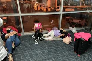 En el piso del aeropuerto, los pasajeros varados aguardan saber cuándo podrán volar a la Argentina.