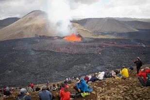 Los espectadores observan los flujos de lava del volcán en Fagradalsfjall, Islandia, a unos 40 kilómetros de la capital Reykjavik, el 10 de agosto de 2022, luego de una erupción que ha estado en curso desde el 3 de agosto de 2022