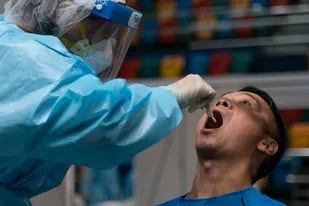 Un trabajador médico recolecta una muestra de hisopado de un hombre en un sitio de prueba improvisado en el Estadio Queen Elizabeth en Hong Kong el 1 de septiembre de 2020