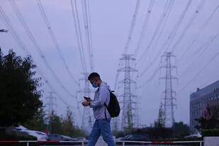 Un hombre camina bajo un vasto enjambre de líneas de electricidad en Pekín