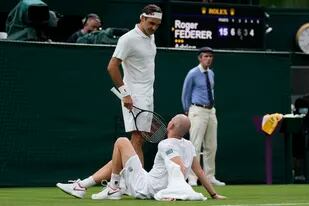 Momento de drama: Roger Federer habla con Adrian Mannarino, tendido en el piso después de la lesión